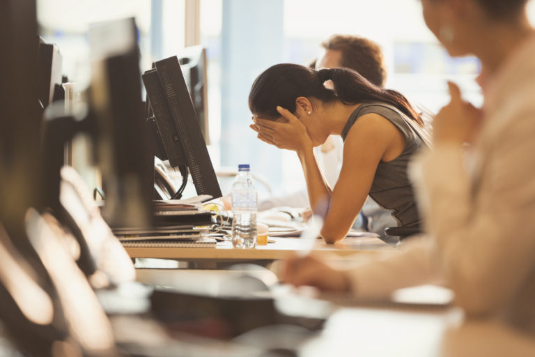 Image of stressed businesswoman with head in hands at office desk