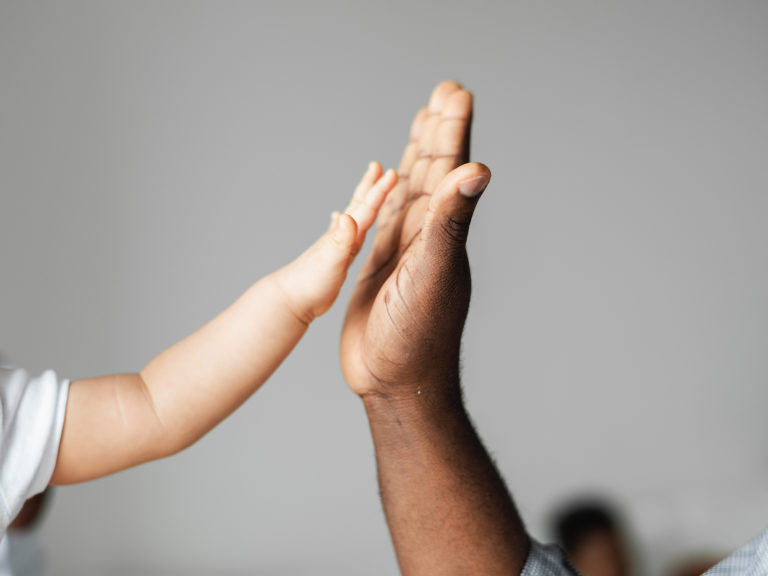 Image of baby hand high-fiving parent's hand