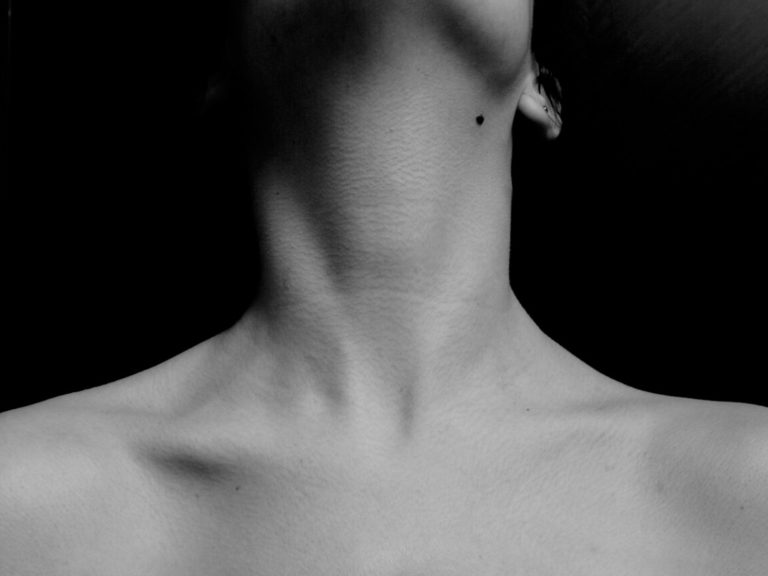 Image of close-up shoulder of woman standing against black background