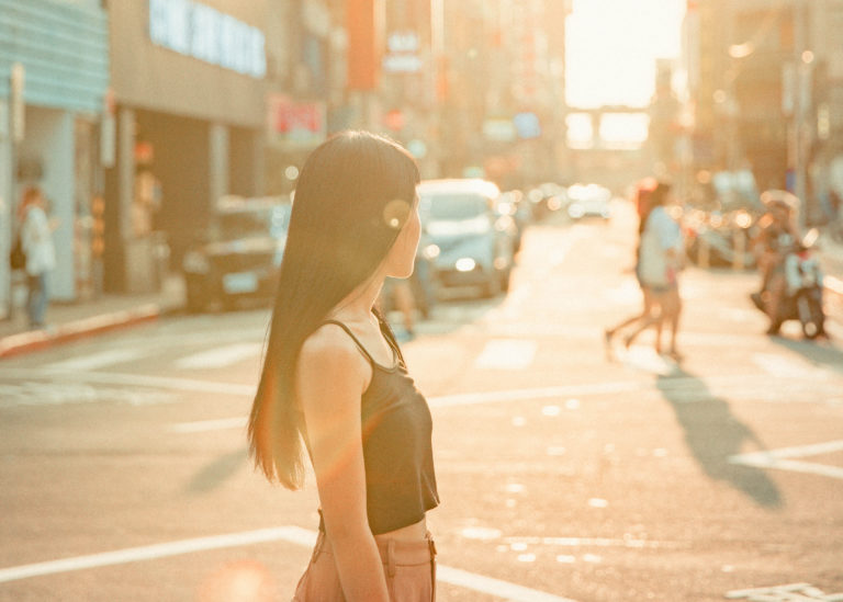 Young asian woman staring into the sunset in the middle of the street