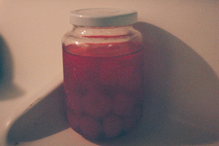 A jar of Maraschino cherries in the door of a refrigerator.